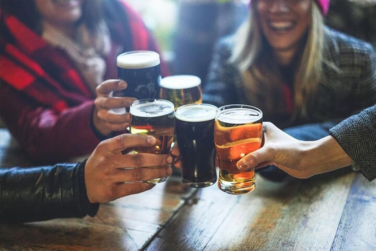 skupina lidí sedících kolem stolu a pijících pivo