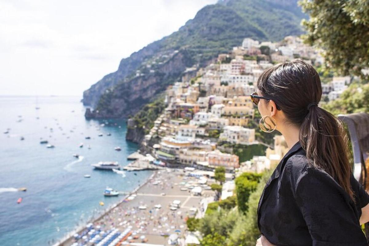 una donna in piedi su una sporgenza che guarda una spiaggia