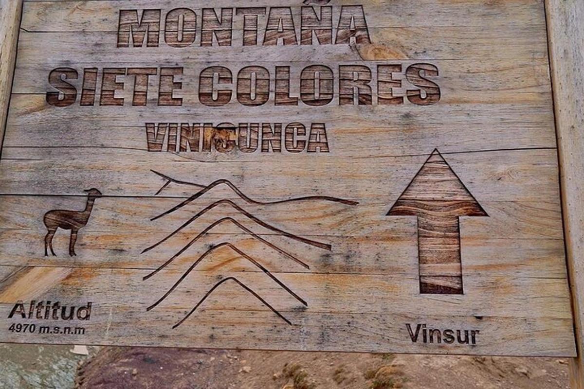 un cartello di legno con una freccia e un cartello che dice colori del fianco della montagna