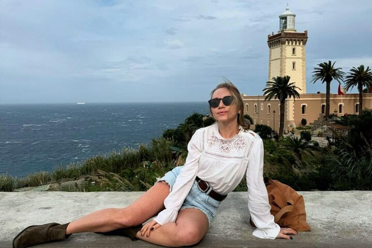 eine Frau, die auf einem Felsvorsprung vor einem Leuchtturm sitzt