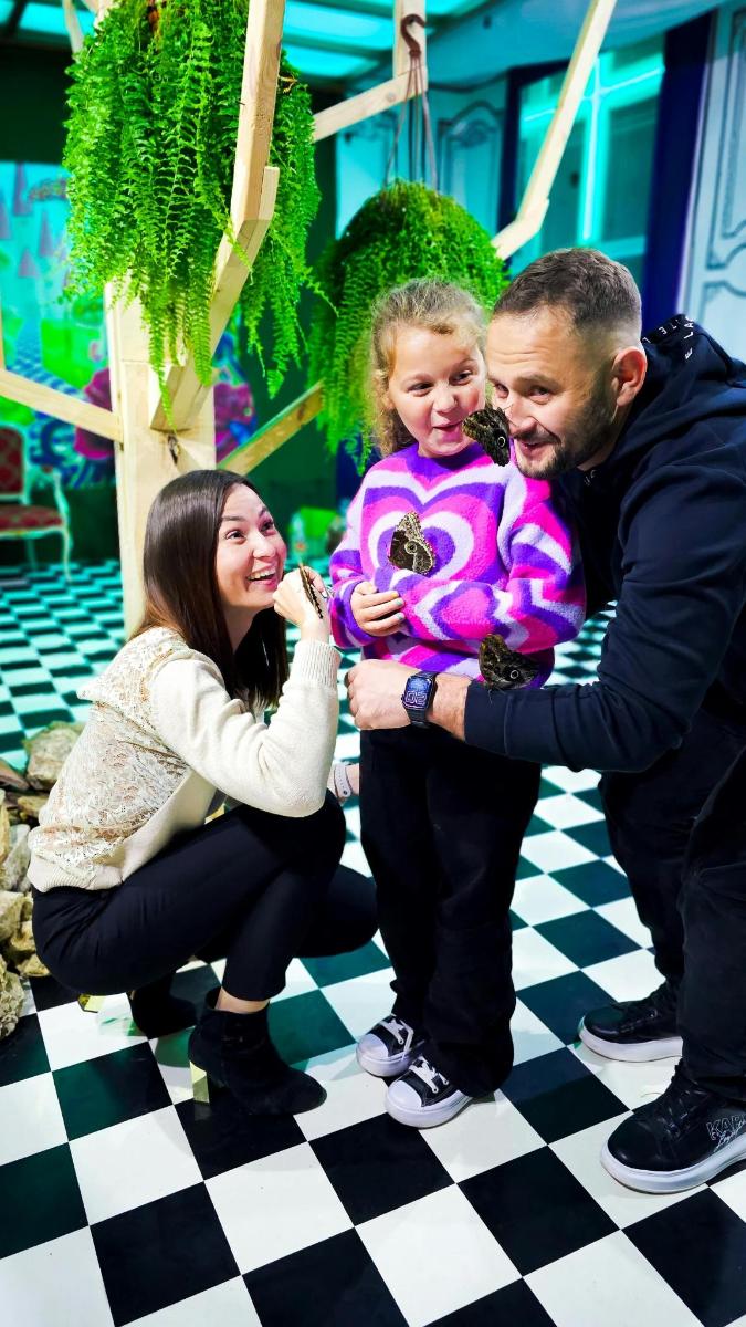 a man and woman holding a little girl on a checkered floor