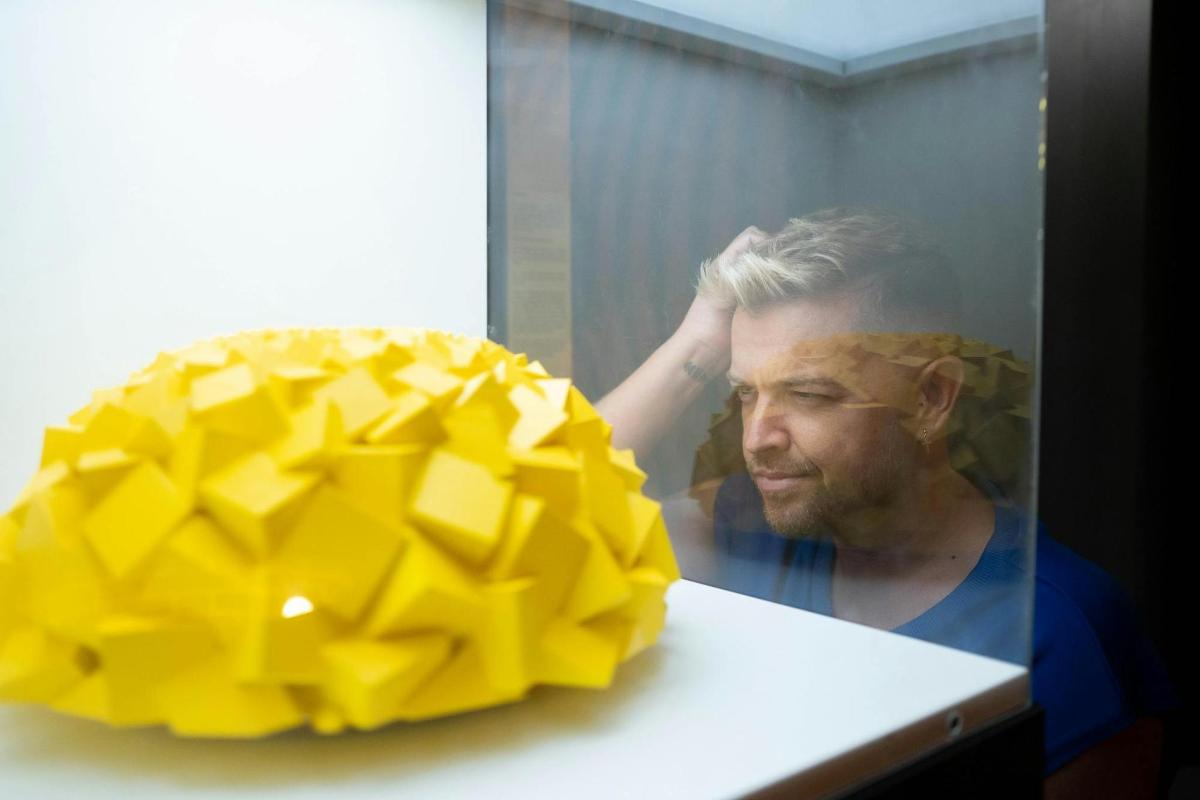 a man in a mirror looking at a yellow object