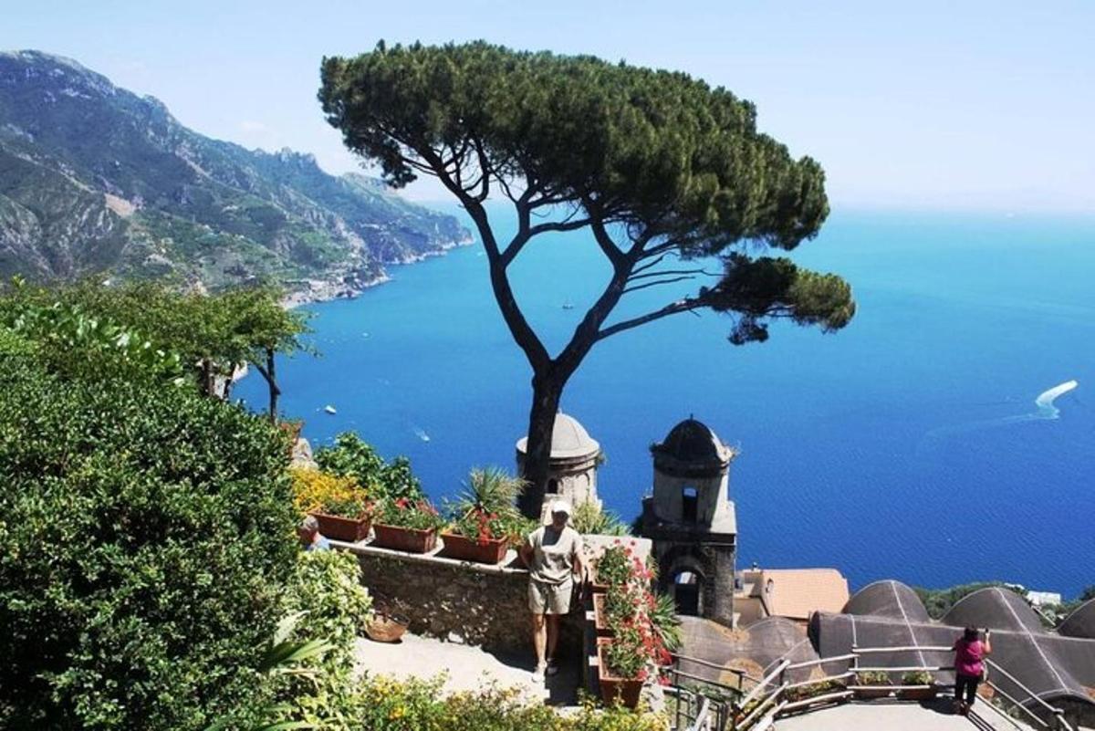 un home dret al costat d'una casa amb un arbre