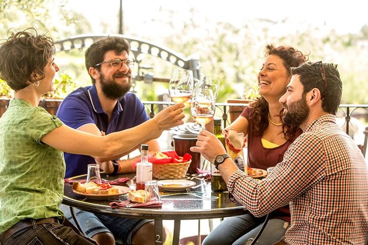 Un grupo de personas sentadas alrededor de una mesa bebiendo vino.