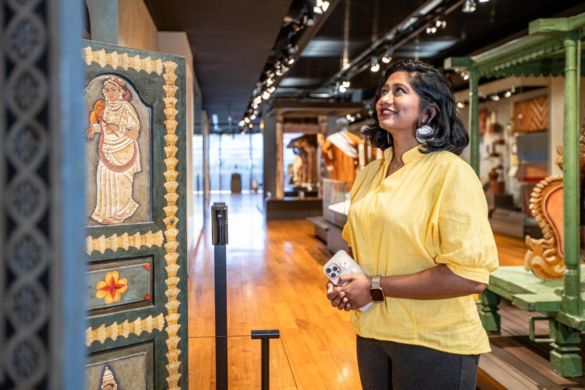 a woman standing next to a painting of a goddess