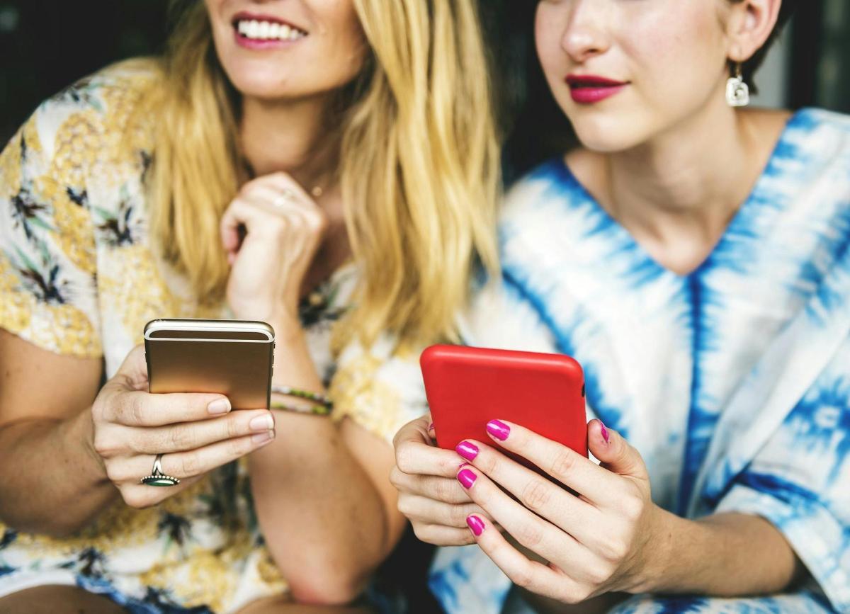 two women are looking at their cell phones