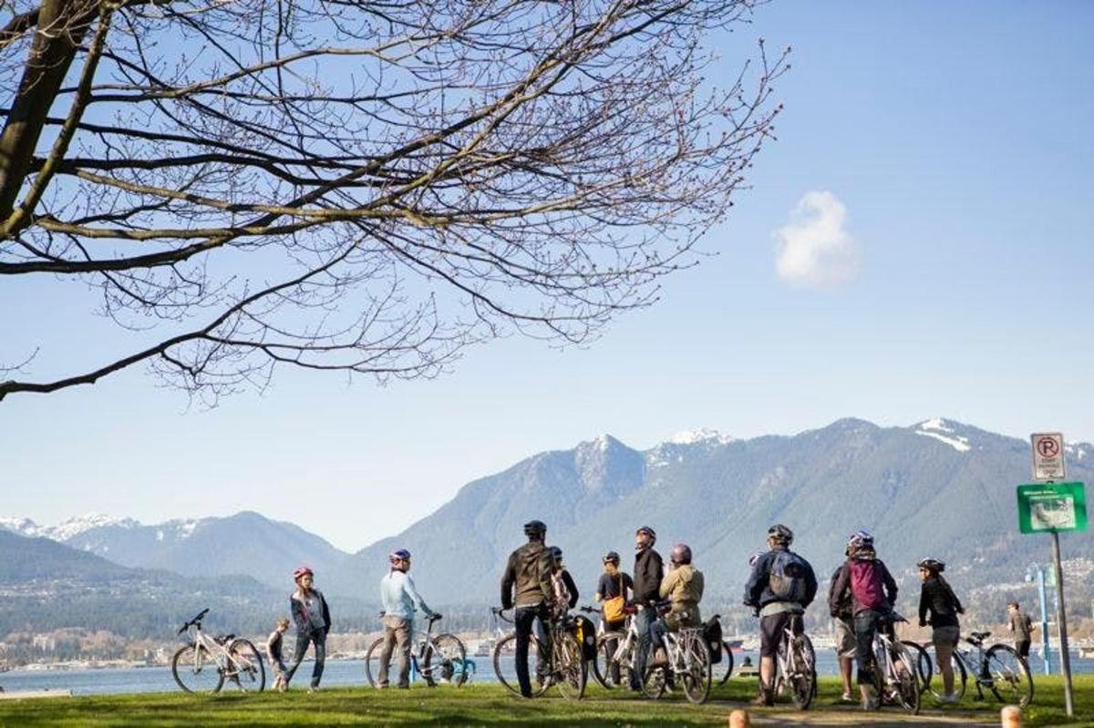 cilvēku grupa, kas brauc ar velosipēdiem pa ceļu