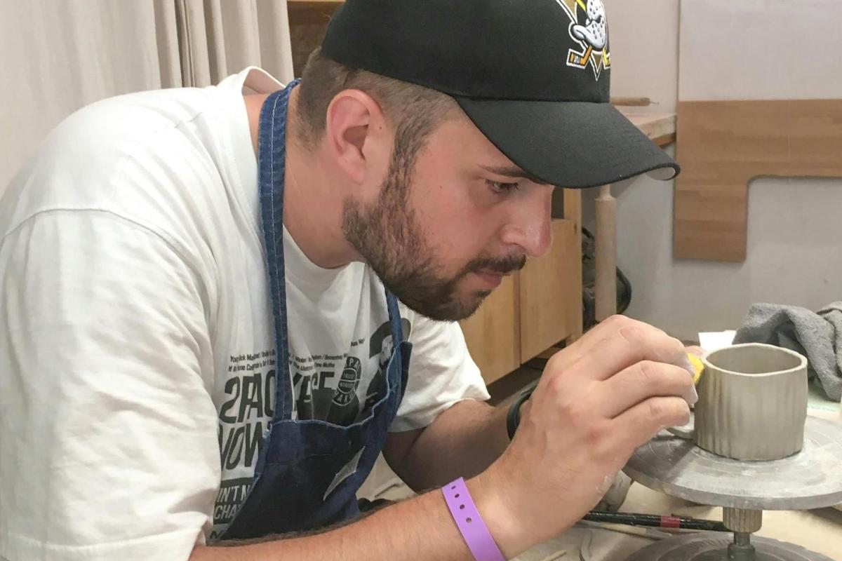 Un hombre está preparando una taza en una mesa.