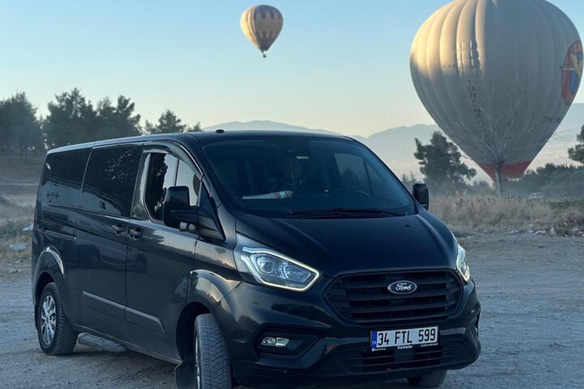o dubă neagră parcată lângă două baloane cu aer cald