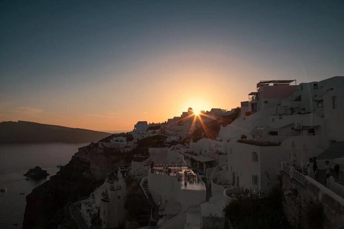 Una puesta de sol sobre un grupo de edificios blancos en un acantilado