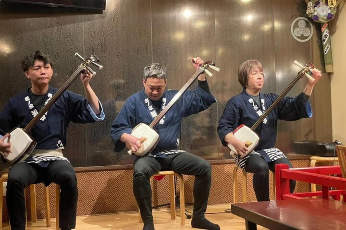 a group of three men sitting in chairs holdingviolins