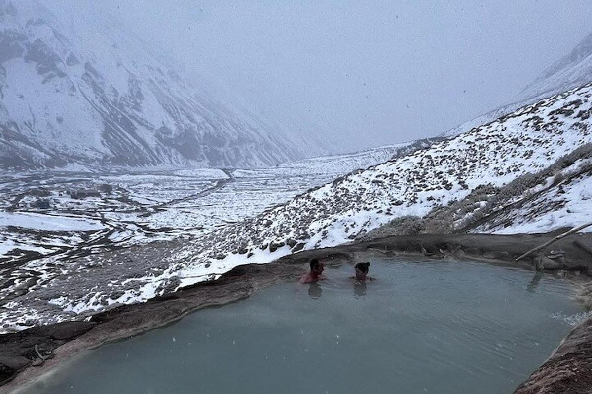 duas pessoas em uma piscina de água ao lado de uma montanha coberta de neve