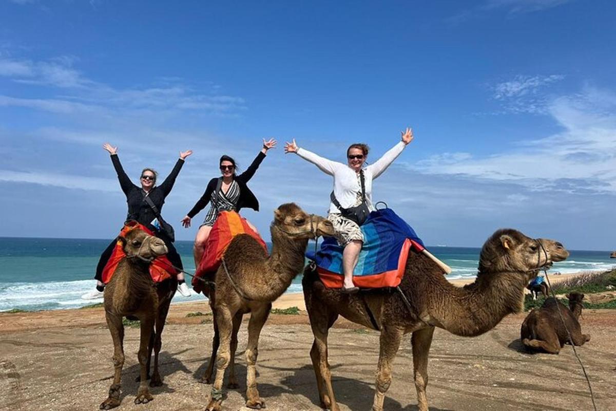 three people riding on camels on the beach