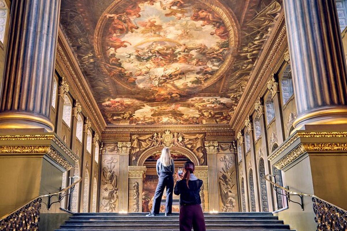 two people standing on stairs in a building with a painting