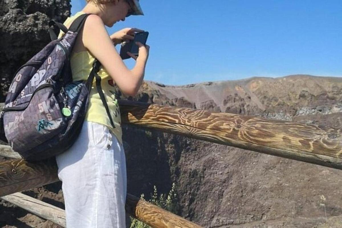 a woman with a backpack taking a picture of the grand canyon