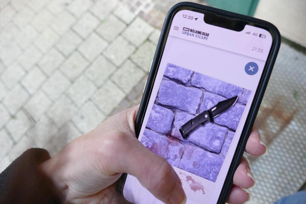 egy személy, aki egy késsel a képernyőn tartja a mobiltelefonját