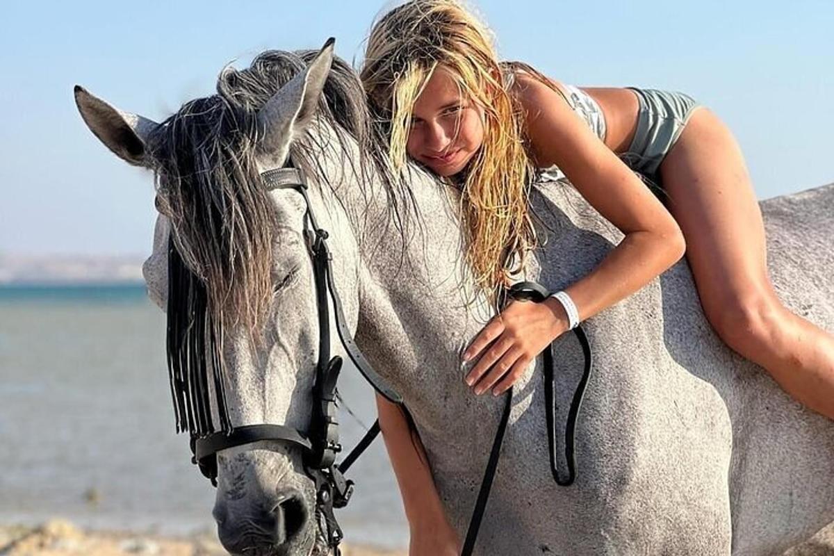 een vrouw omhelst een paard op het strand