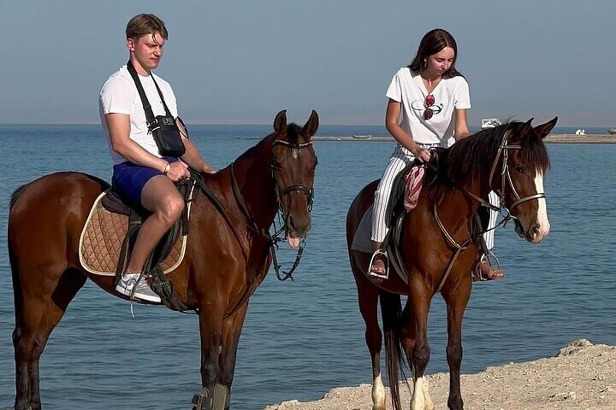 en mann og en kvinne som rir på hester på stranden