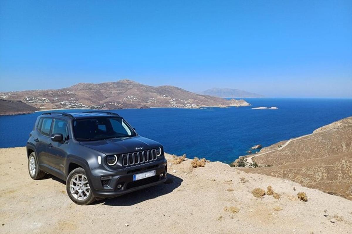 una jeep blu parcheggiata in cima a una collina vicino all'oceano