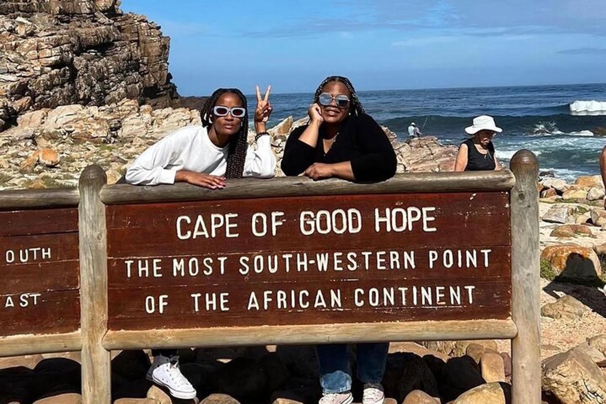 two people standing on a sign at the beach