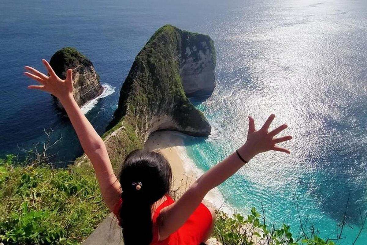 seorang wanita duduk di atas tebing dengan tangannya di udara