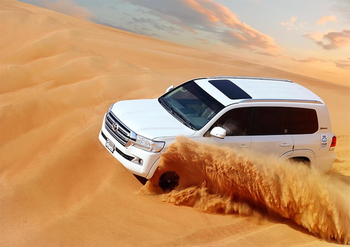 a white truck driving through the sand in the desert