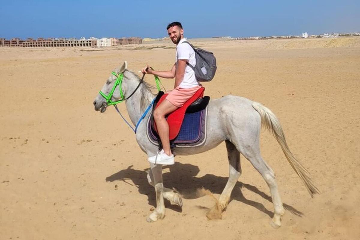 muž jedoucí na koni na pláži