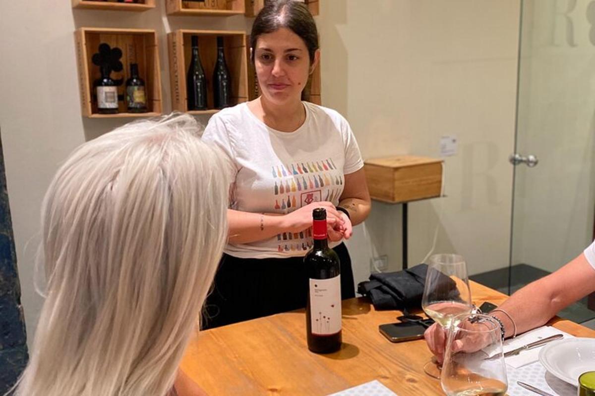 žena stoji za stolom s bocom vina