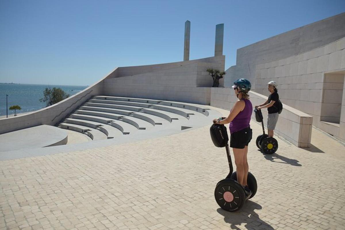 two women riding on scooters in front of a building