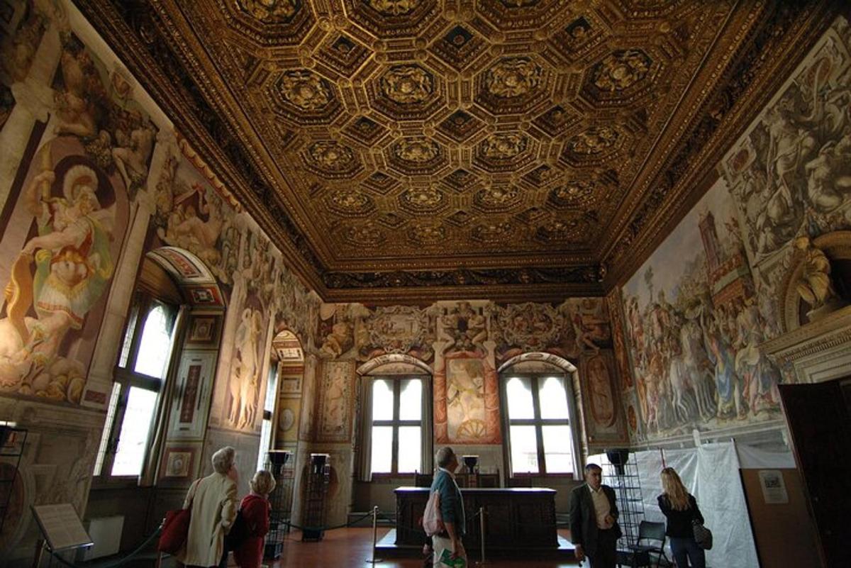 a group of people walking around a room with paintings on the ceilings