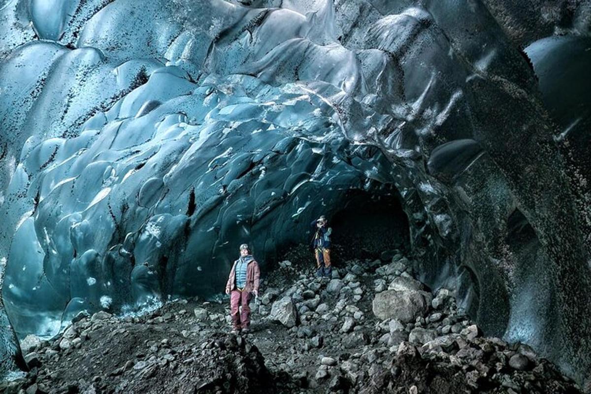 duas pessoas em pé em frente a uma caverna de gelo