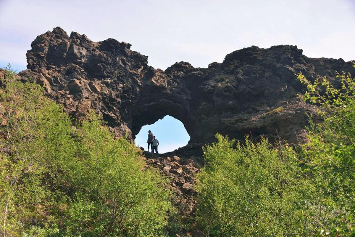 seseorang yang berdiri di hadapan sebuah gua di sebuah gunung