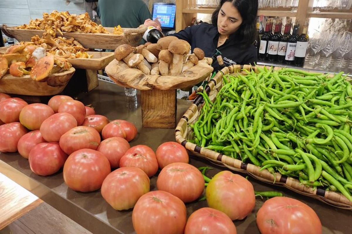 seorang wanita berdiri di belakang kaunter dengan buah-buahan dan sayur-sayuran