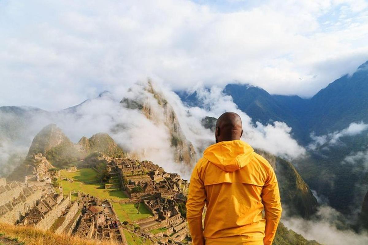 Un hombre parado en la cima de una montaña con vistas a una ciudad.
