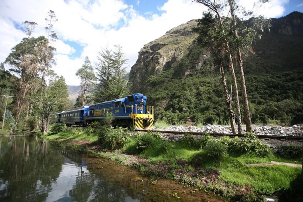 kereta api biru dan kuning yang bergerak menyusuri landasan di sebelah sungai