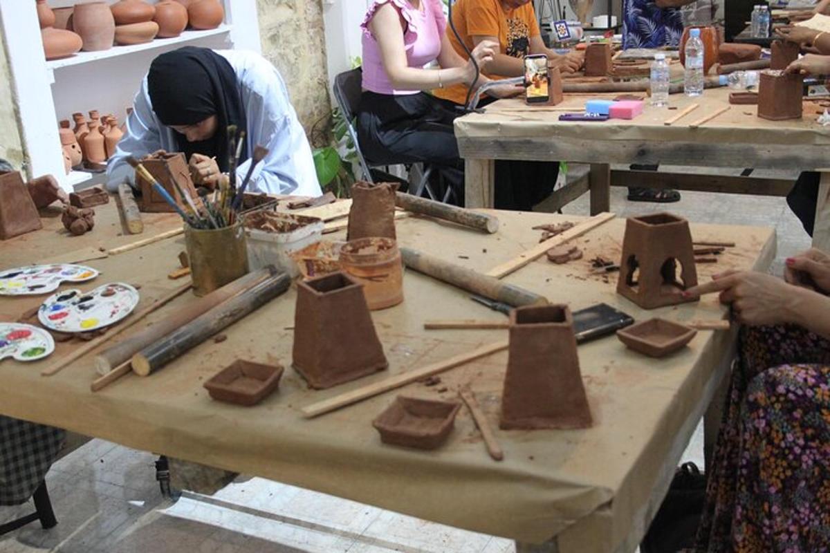 Un grupo de personas sentadas alrededor de una mesa haciendo cerámica.