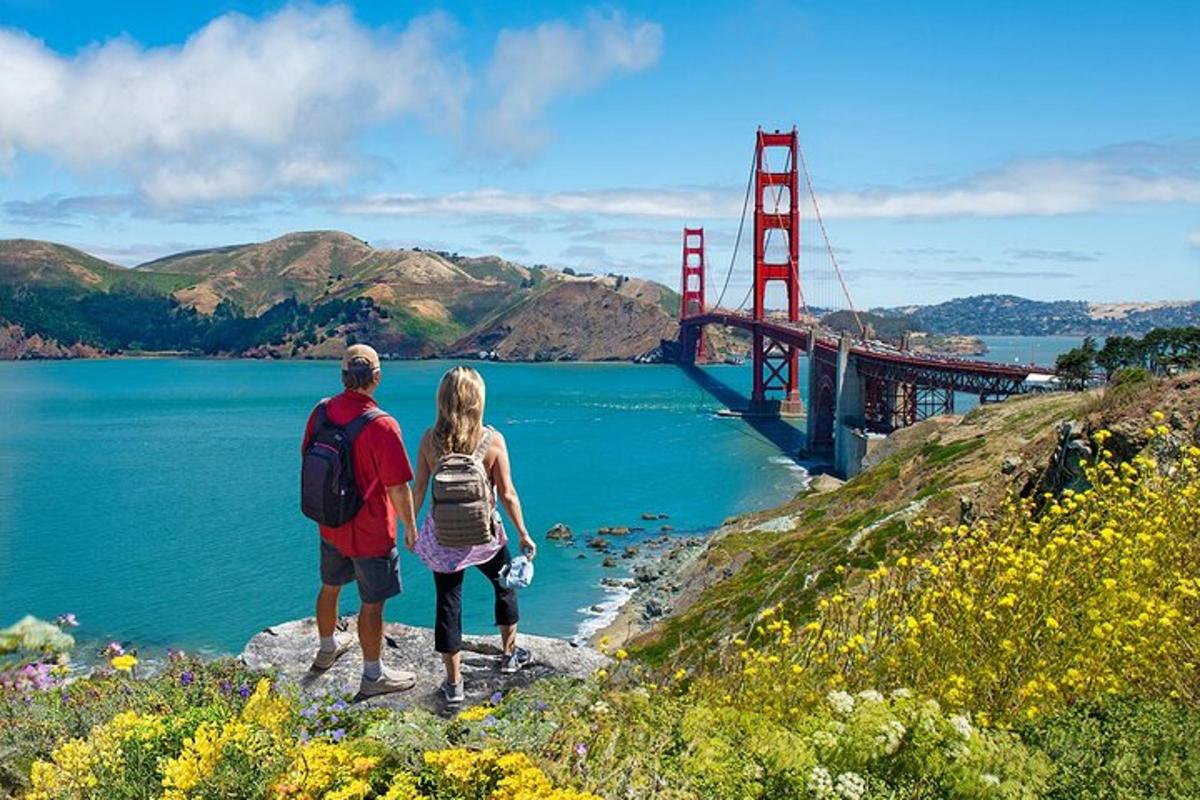 un uomo e una donna in piedi su una roccia vicino al Golden Gate Bridge