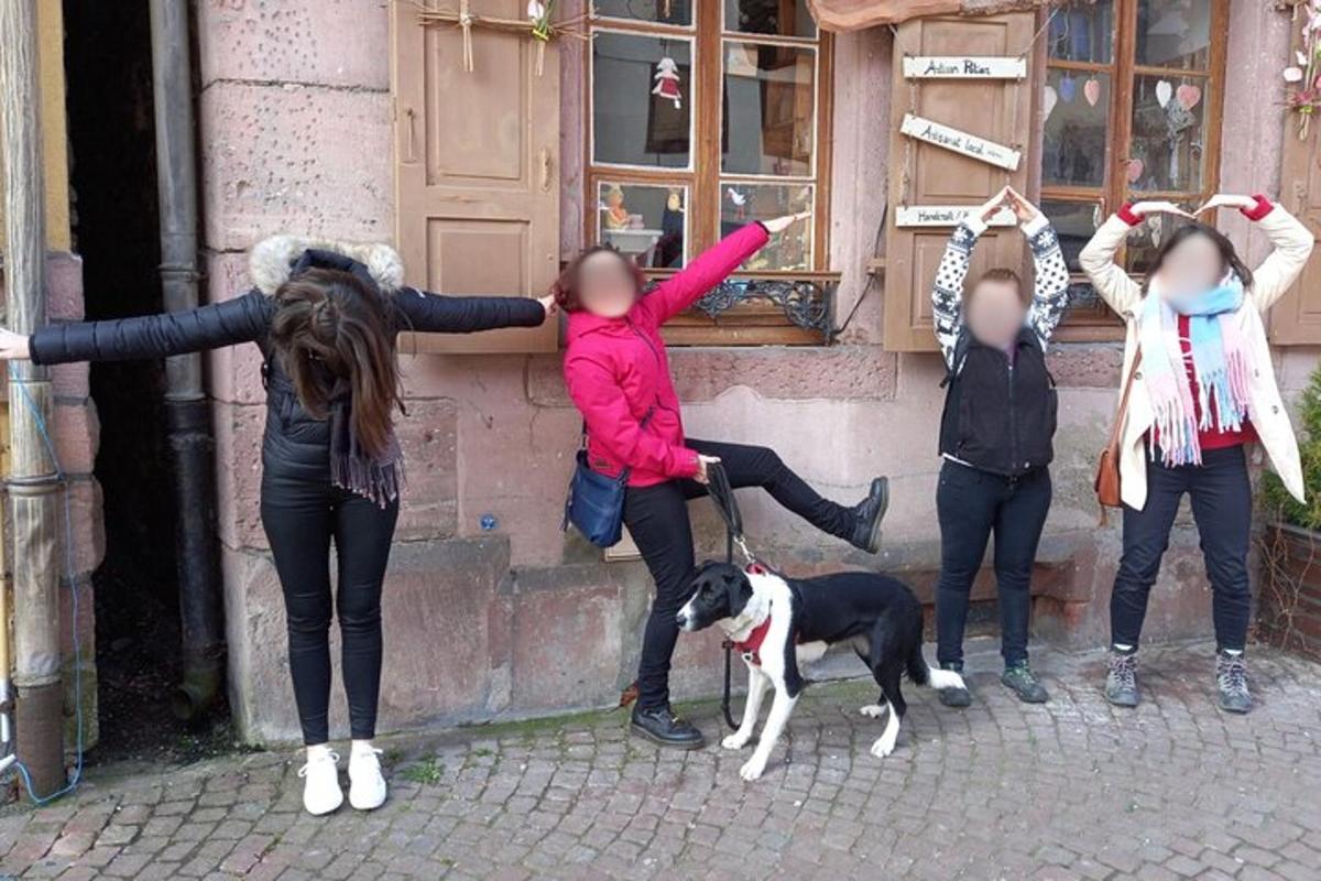 um grupo de meninas em pé ao lado de um prédio com um cachorro