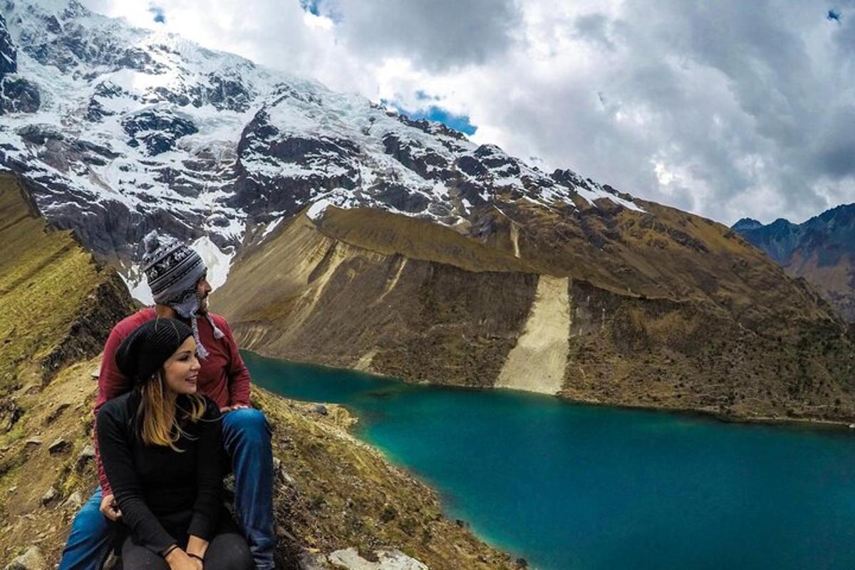 dva človeka sedita na gori s pogledom na jezero