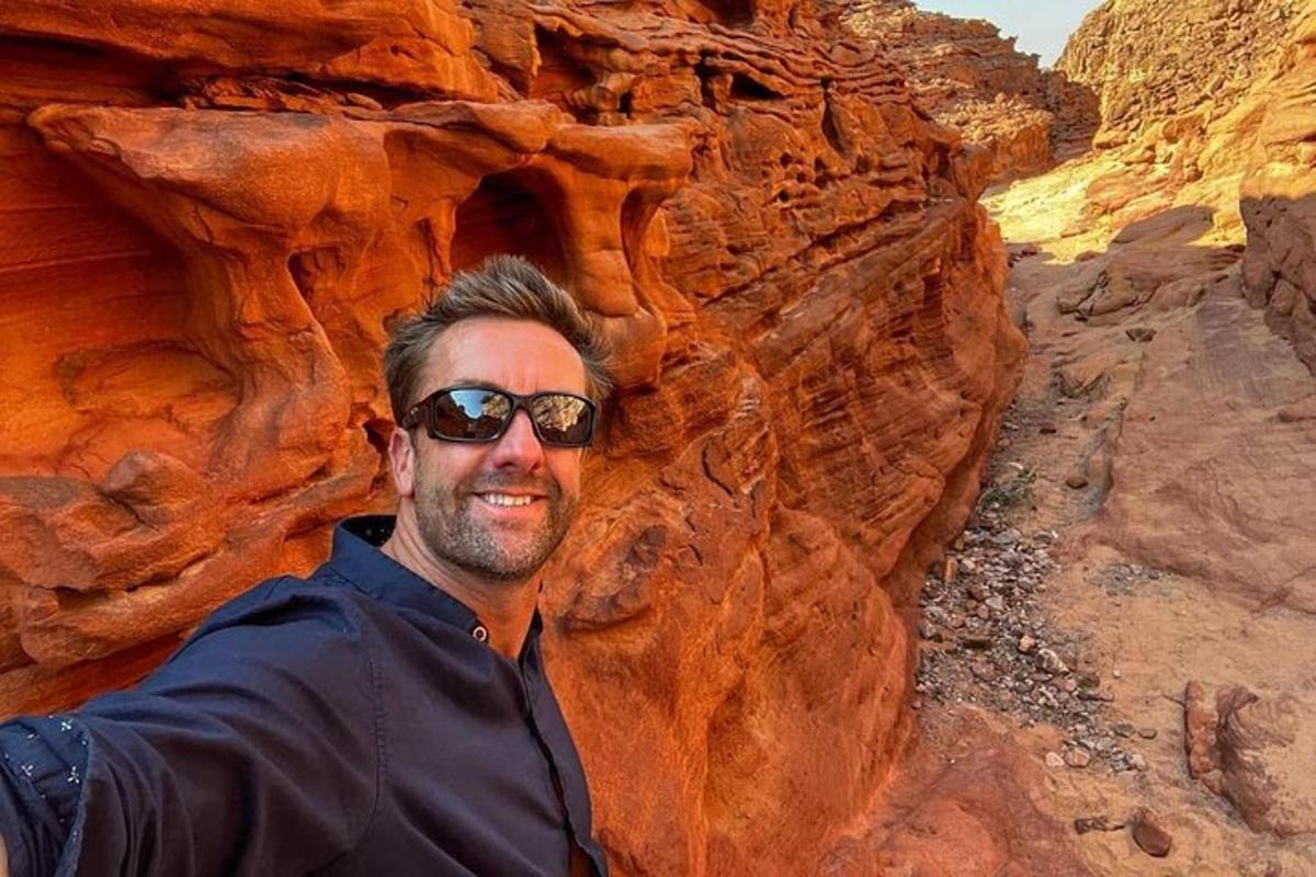Un hombre con gafas de sol está parado en un cañón.