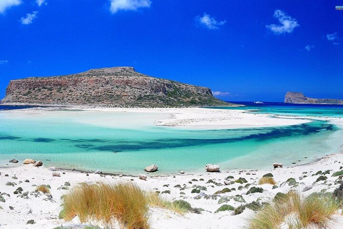 pantai dengan air biru dan gunung di latar belakang