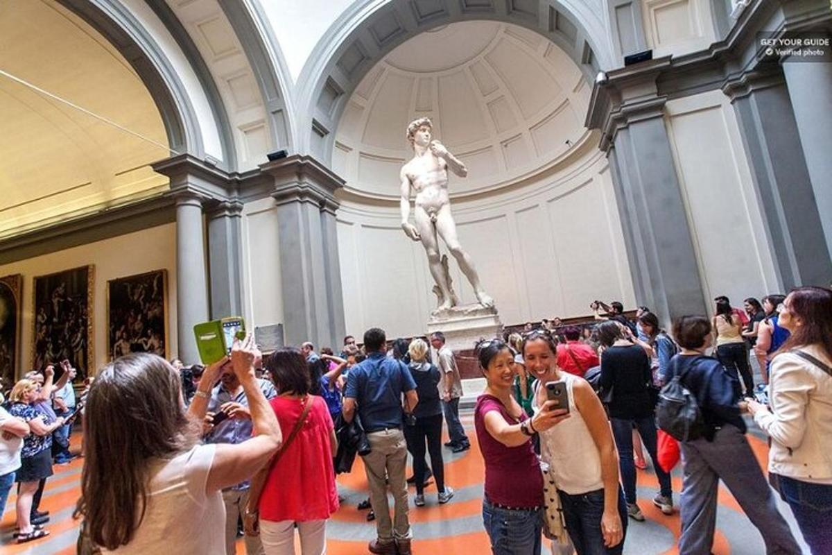Una multitud de personas tomando fotografías de una estatua en un museo.