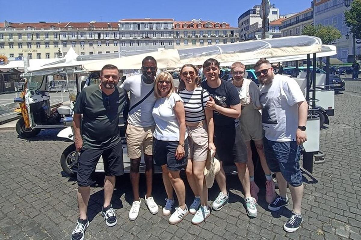 un grup de oameni care pozează pentru o fotografie în fața unei mașini