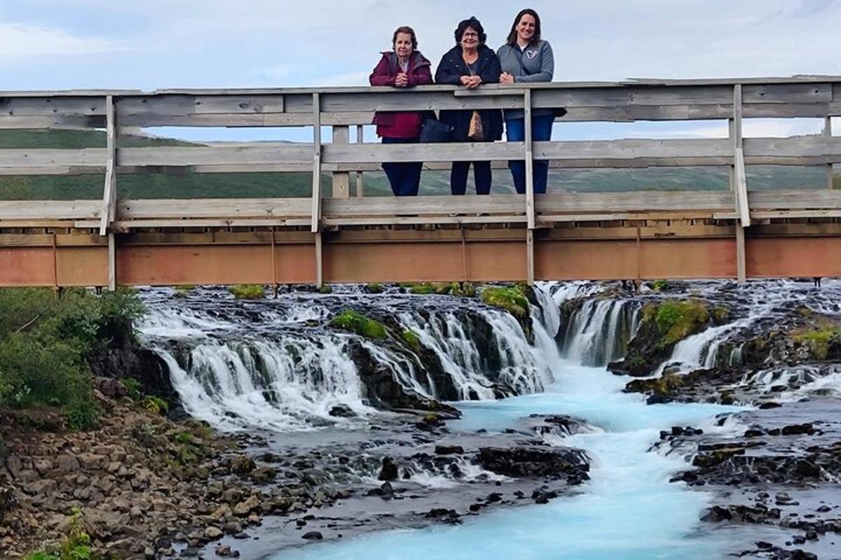 tres dones dempeus en un pont sobre una cascada