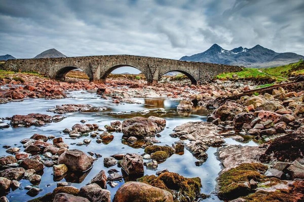 un ponte sopra un fiume con rocce e montagne