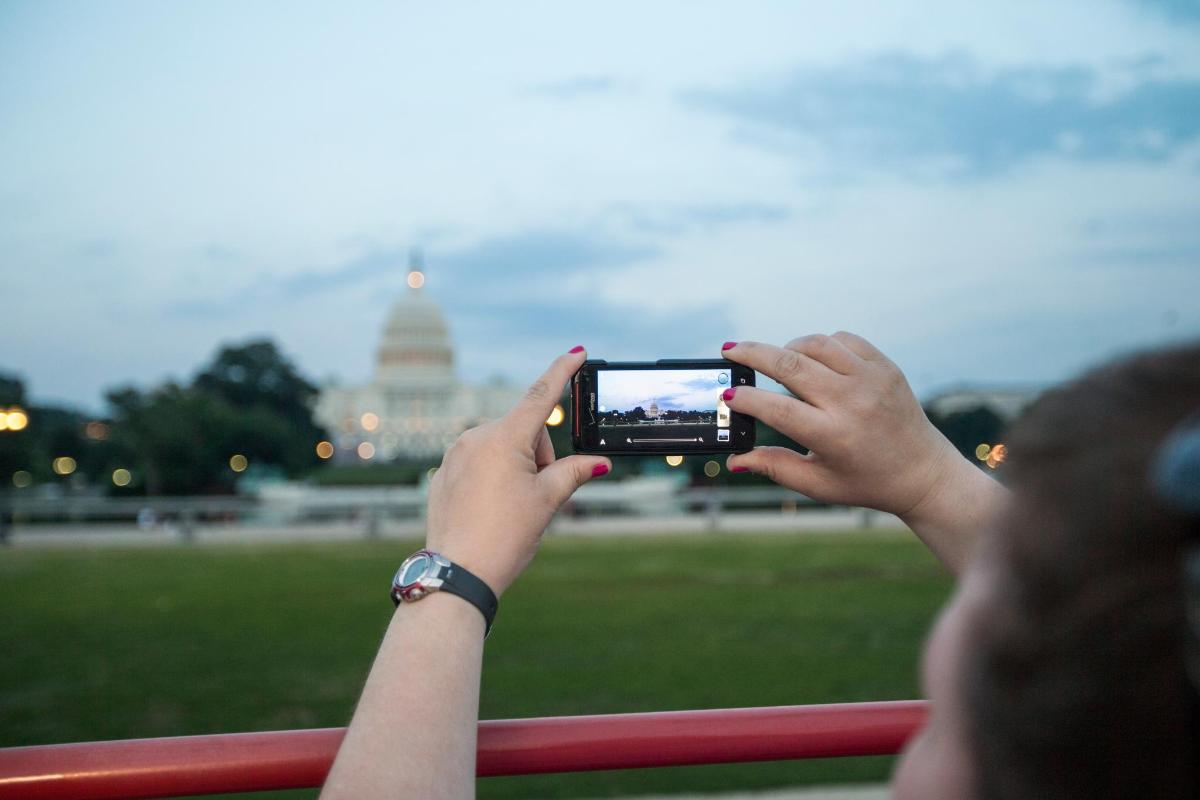 a woman taking a picture of the capitol building with her cell phone