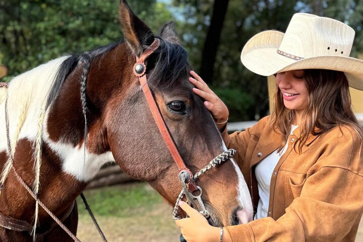 una donna con un cappello da cowboy che accarezza un cavallo