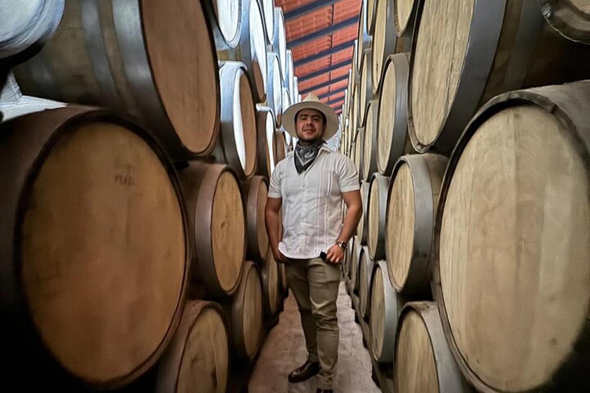 un uomo in piedi in un mucchio di botti di vino