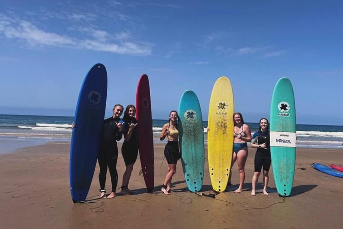 un gruppo di donne in piedi sulla spiaggia con le loro tavole da surf