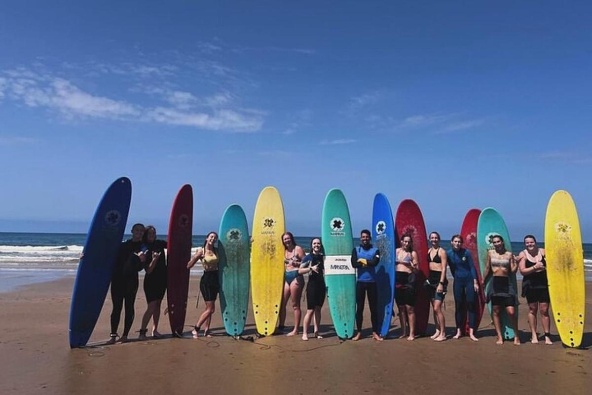un gruppo di persone che tengono le loro tavole da surf sulla spiaggia